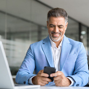 gentleman sitting in front of a computer on his phone